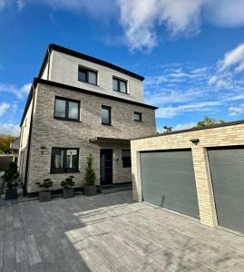 Una gran casa de ladrillo con dos puertas de garaje. en Modernes deluxe Apartment für 4 Pers in Kaarst Nähe Düsseldorf, en Kaarst