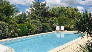 a swimming pool in a garden with a chair at Domaine de la Ronce in Cézac