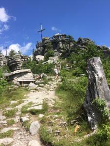 a person walking on a rocky hill with a cross at Ferienwohnung In Frauenberg Mit Garten in Haidmühle