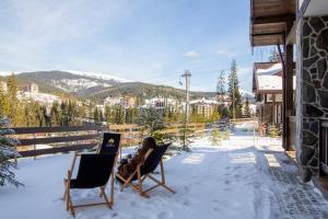een persoon zittend in stoelen op een veranda in de sneeuw bij Die SONNE in Boekovel