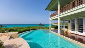 a house with a swimming pool next to the ocean at Villa Oasis Anguilla in Long Bay Village
