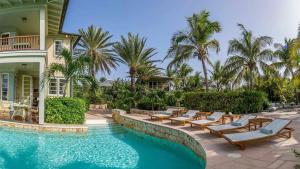 a swimming pool with lounge chairs and a house at Villa Oasis Anguilla in Long Bay Village