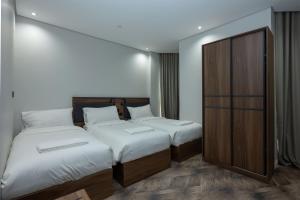a bedroom with two beds and a wooden cabinet at Samama Almaqam Ajyad Hotel Makkah in Mecca +75 photos