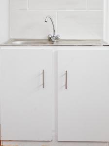 a kitchen with white cabinets and a sink at LUX IN THE AIR - An Elevated Experience on the Vaal Dam in Denysville