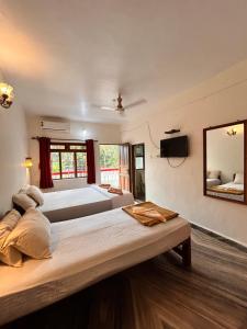 two large beds in a room with a mirror at Maria Paulo Guest House Bar and Restaurant in Agonda