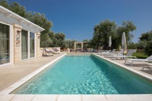 a swimming pool with chaise lounge chairs next to a house at Terra Mater - Exclusive Cottage - in Ostuni