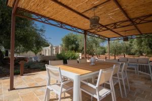 a wooden table and chairs under a wooden pergola at Terra Mater - Exclusive Cottage - in Ostuni