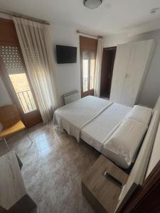 Un dormitorio con una cama blanca y un televisor. en Hostal Marcela Berge, en Berge