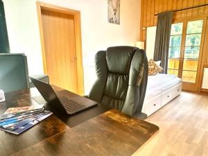 a office with a desk with a laptop and a chair at Chalet with Scenic Valley & Mountain Views in Lütschental
