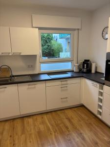 a kitchen with white cabinets and a window at Ferienwohnung am Engelmannsberg in Hattenheim