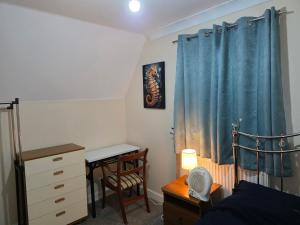 Un dormitorio con una cortina azul y un escritorio y una cama. en Stay Near Colchester twn centre5, en Hythe