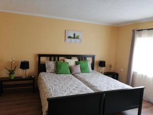 a bedroom with a large bed with green pillows at Téged Vártunk Vendégház in Bakonyoszlop