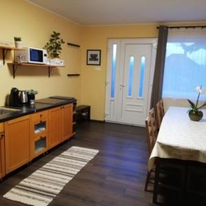 a room with a kitchen with a table and a door at Téged Vártunk Vendégház in Bakonyoszlop +18 photos