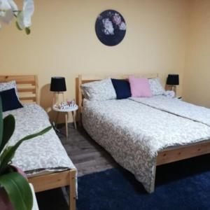 a bedroom with two beds and a clock on the wall at Téged Vártunk Vendégház in Bakonyoszlop