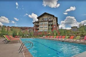 a hotel with a swimming pool with chairs and a building at Base Camp One 403 in Granby