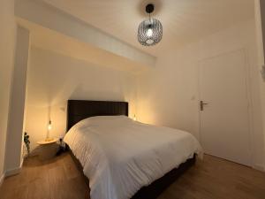 ein Schlafzimmer mit einem großen weißen Bett und einer Lampe in der Unterkunft T2 neuf marbre et or - écran géant - Netflix in LʼHermitage