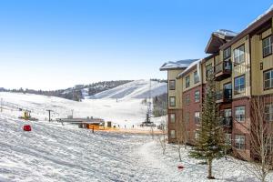 a building with a snow covered slope next to a mountain at Base Camp One 201 in Granby