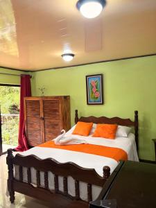 a bedroom with a bed with orange pillows at Hospedaje Angeluz in Quesada