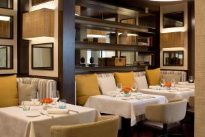 ボローニャにあるスターホテルズ エクセルシオールの白いテーブルクロスがかけられたテーブルと椅子のあるレストラン