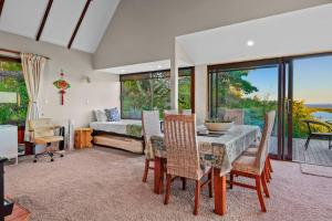 ein Esszimmer mit einem Tisch und Stühlen sowie ein Schlafzimmer in der Unterkunft Tranquil West Haven with Water and Skyline Views in Auckland