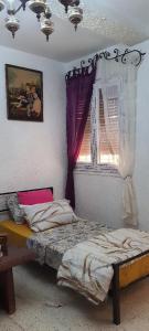 een slaapkamer met een bed en een raam bij F3 Mostaganem vue sur la Mer in Mostaganem +5 foto's
