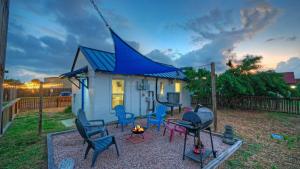 Ein kleines Haus mit blauem Dach, Stühlen und einem Feuer in der Unterkunft Walk to Alister St Near Dining King Suite w Private Yard Fire Pit Casa Santori by AvantStay in Port Aransas