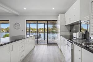 a kitchen with white cabinets and a view of the water at Dora Creek Escape with Pool and Spa in Dora Creek