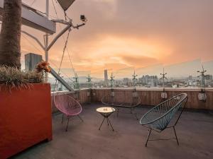 a patio with chairs and a table on a roof at The Urban Muse suite in Mexico City