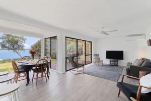 a living room with a table and a couch at Lakeside Getaway Halekulani in Budgewoi +7 photos