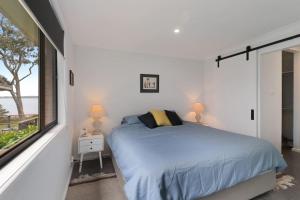 a white bedroom with a bed and a window at Lakeside Getaway Halekulani in Budgewoi