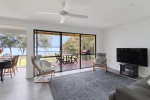 a living room with a couch and a television and a table at Lakeside Getaway Halekulani in Budgewoi