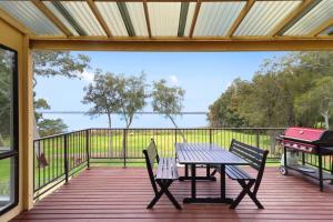 a wooden deck with a picnic table and a grill at Lakeside Getaway Halekulani in Budgewoi
