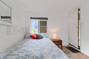 a bedroom with a bed and a desk and a window at Lakeside Getaway Halekulani in Budgewoi +7 photos