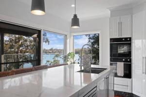 a kitchen with white cabinets and a large window at Bayview Bliss Brightwaters in Morisset East