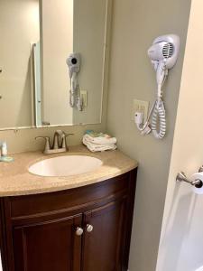 a bathroom with a sink and a mirror and a hair dryer at Loon Mountain Escape Comfortable Room Near Everything in Lincoln