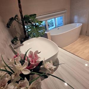 a bathroom with a tub and a vase of flowers on a table at Our Time Staycation in Ban Chak Makham
