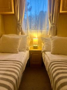 two beds in a room with a window and a lamp at East Coast in Port Seton
