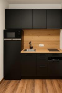 a black kitchen with a sink and a refrigerator at TinyAlps in Saalbach Hinterglemm