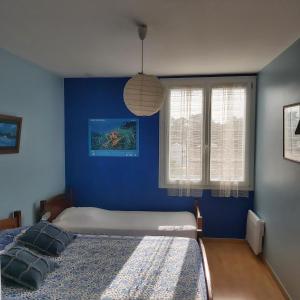 ein blaues Schlafzimmer mit einem Bett und zwei Fenstern in der Unterkunft Les flots bleus face à la mer in Notre-Dame-de-Monts
