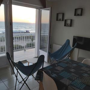 ein Esszimmer mit einem Tisch und Stühlen sowie einem Balkon in der Unterkunft Les flots bleus face à la mer in Notre-Dame-de-Monts