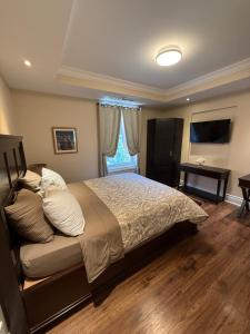 Un dormitorio con una cama grande y un televisor. en The Century House Bed and Breakfast Ottawa, en Ottawa
