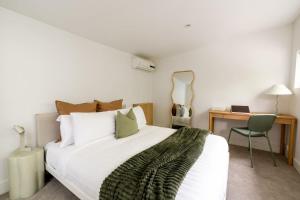 a bedroom with a bed with a desk and a chair at Chic Seddon Retreat Near the CBD in Seddon
