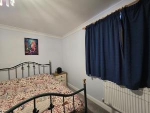 a bedroom with a bed and a blue curtain at Home away from city noise Be in Hythe
