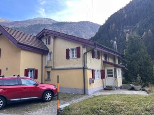 a red car parked in front of a house at Dammablick Göschenen in Göschenen