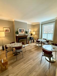 sala de estar con mesas, sillas y chimenea en The Century House Bed and Breakfast Ottawa, en Ottawa