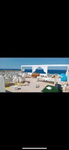 een uitzicht op een strand met witte stoelen en parasols bij Villa ziari in Skikda