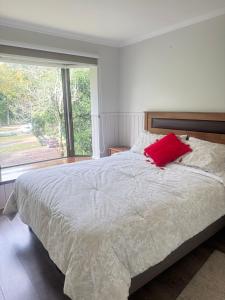 a bedroom with a bed with a red pillow on it at Parque suizo, Pucon in Pucón +18 photos