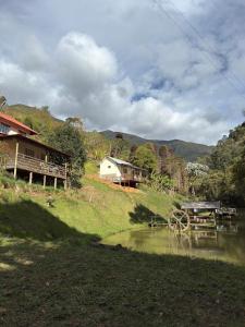 Una casa en una colina con una mesa de picnic y un estanque. en Chalé Roda Dágua C, en Caparaó Velho