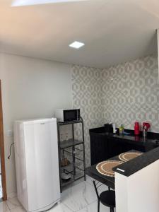 Una cocina con un refrigerador blanco y una mesa. en Chalé Roda Dágua C, en Caparaó Velho