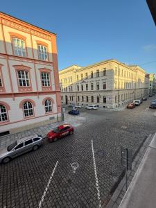 a city street with cars parked in front of buildings at Veleslaveenka in Plzeň